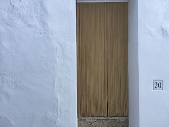 Beaded curtain on doorway of white house with number