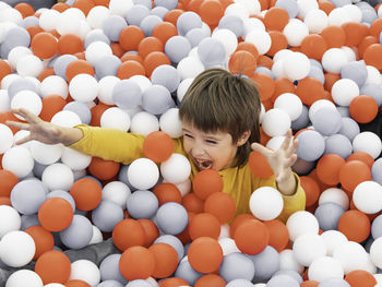 Laughing boy plays in ball pit. plastic balls in dry paddling pool.playroom at kindergarten. 