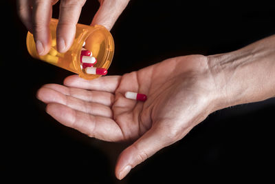 Close-up of woman holding hands over black background