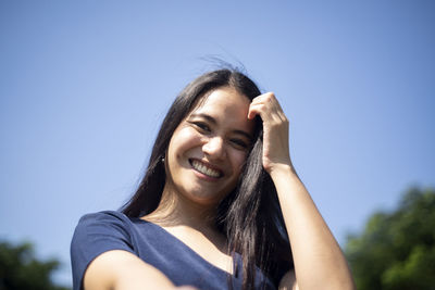 Portrait of a smiling young woman against blue sky