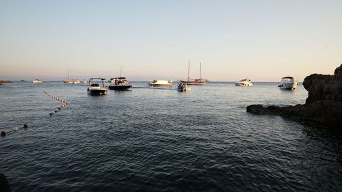 Boats in sea against clear sky