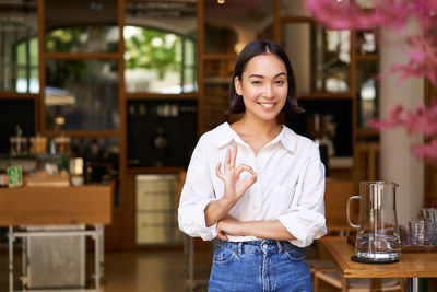Portrait of young woman standing in cafe