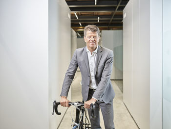 Portrait of smiling businessman with bicycle on office floor