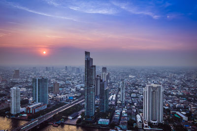 High angle view of modern buildings in city against sky during sunset