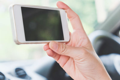 Close-up of hand holding mobile phone in car
