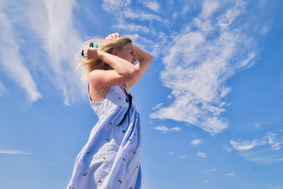 Low angle view of woman standing against blue sky