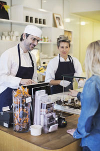 Cafe worker attending female customer at counter