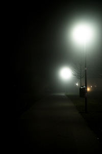 Illuminated street light on road at night