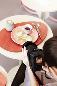 High angle view of woman photographing food on table
