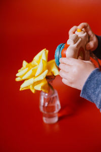 Close-up of hand holding apple against red background