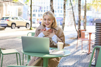 Young woman using laptop at cafe