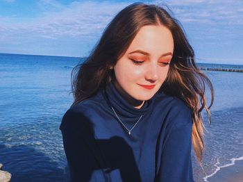 Portrait of beautiful young woman against sea