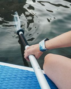 Midsection of woman holding oar at lake