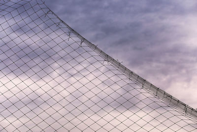 Low angle view of fence against cloudy sky