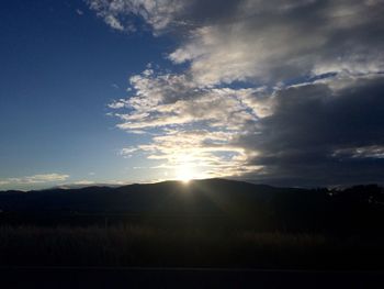Sun shining through clouds over landscape