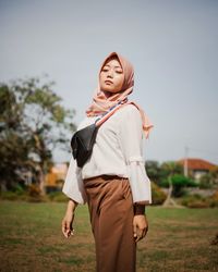 Full length of young woman standing on field against sky