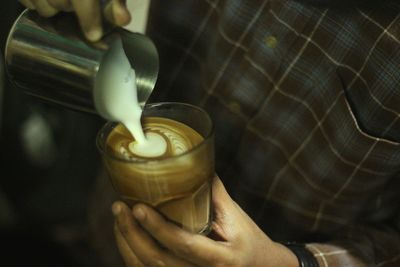 Close-up of hand pouring coffee cup