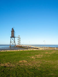 Lighthouse by sea against clear sky