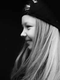 Close-up of young woman against black background