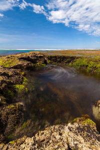 Scenic view of waterfall against sky