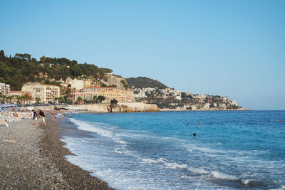 People on beach against clear blue sky
