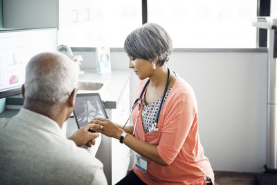 Female doctor explaining x-ray to patient on tablet computer in clinic