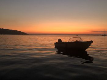 Silhouette boat in sea against sky during sunset