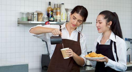 Young woman holding food while standing on table