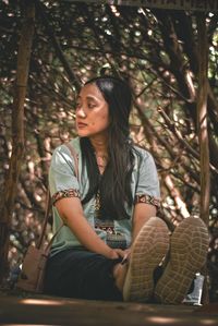 Young woman looking away while sitting in park