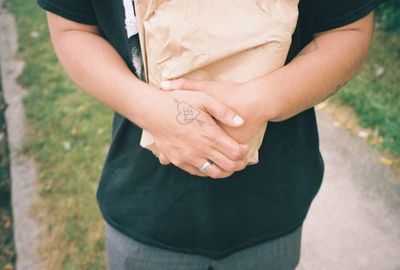 Midsection of woman holding hands while standing outdoors