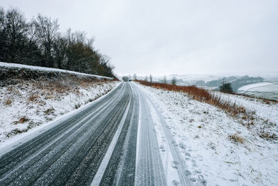 Snow covered road against sky