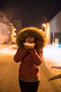 Woman blowing snow at night