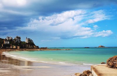 Scenic view of beach against cloudy sky