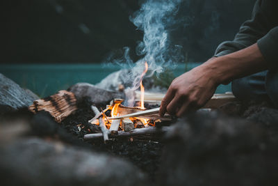 Midsection of man preparing fire on barbecue grill