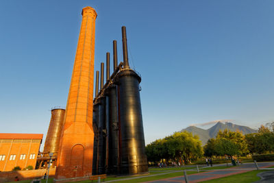 Low angle view of factory against clear blue sky