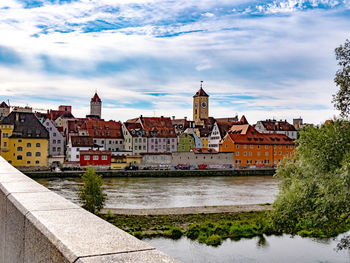 Buildings by river against sky