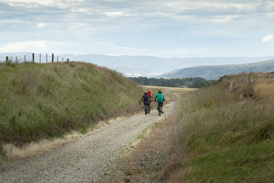 Rear view of people walking on road against sky