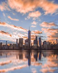 City at waterfront against cloudy sky