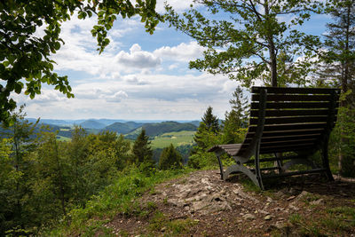 Empty bench on landscape against sky