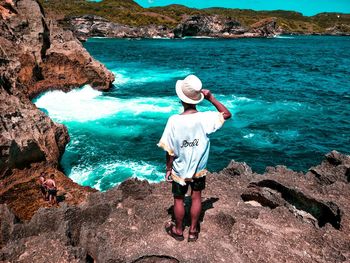 Rear view of man standing on rock at beach