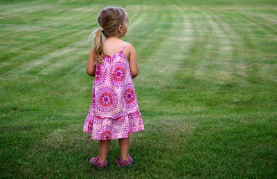 Rear view full length of girl standing on grassy field