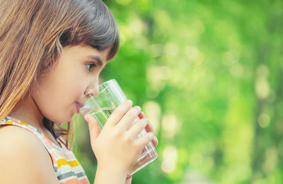 Cute girl drinking water while standing outdoors