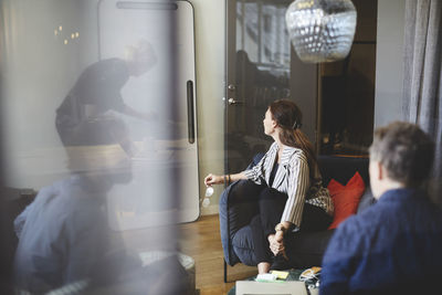 Professionals seen from glass in board room during meeting at creative office