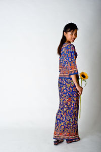 Portrait of woman with sunflower standing against white background