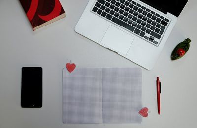 High angle view of mobile phone by paper and laptop with heart shape on table