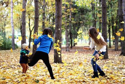 Mother playing with son and daughter at park during autumn