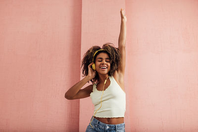 Portrait of young woman standing against wall