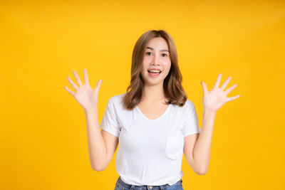 Portrait of a smiling young woman against yellow background