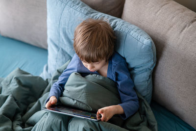 High angle view of boy sitting on sofa