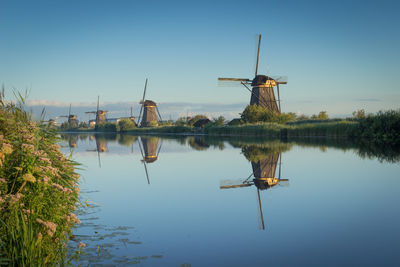 Traditional windmill by lake against sky